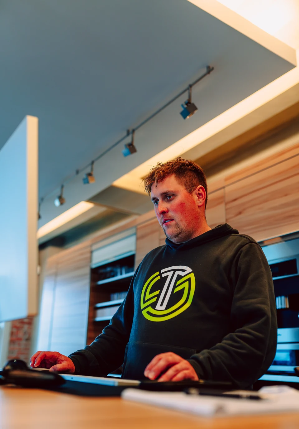 A Stick & Tin team member working at a computer in a branded hoodie